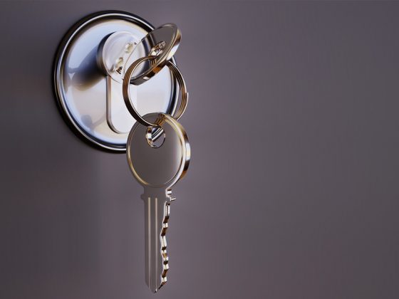 In einem glänzenden, silbernen Schloss steckt ein ebenfalls glänzender, silberner Schlüssel, an dem an einem Ring ein zweiter Schlüssel hängt.