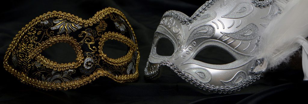 Zwei halbe venezianische Augenmasken liegen sich auf schwarzem Samt so gegenüber, dass sie ein Ganzes bilden. Sie sind beide mit Ornamenten bestickt, die eine Maske ist silbern, die andere schwarz und mit goldenen Säumen verziert.