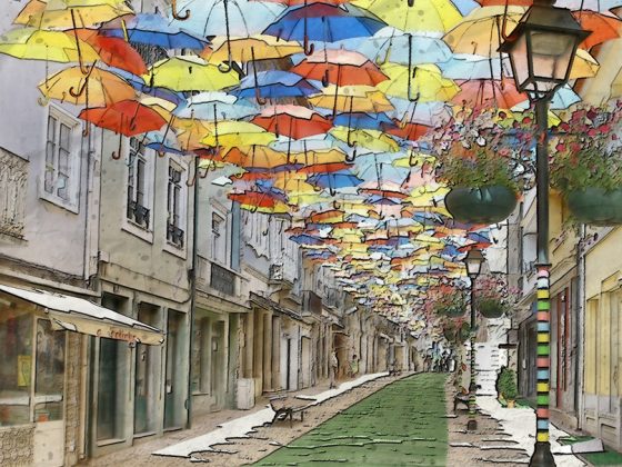 Eine Straße in einem kleinstädtischen Ort wird von bunten Regenschirmen überspannt